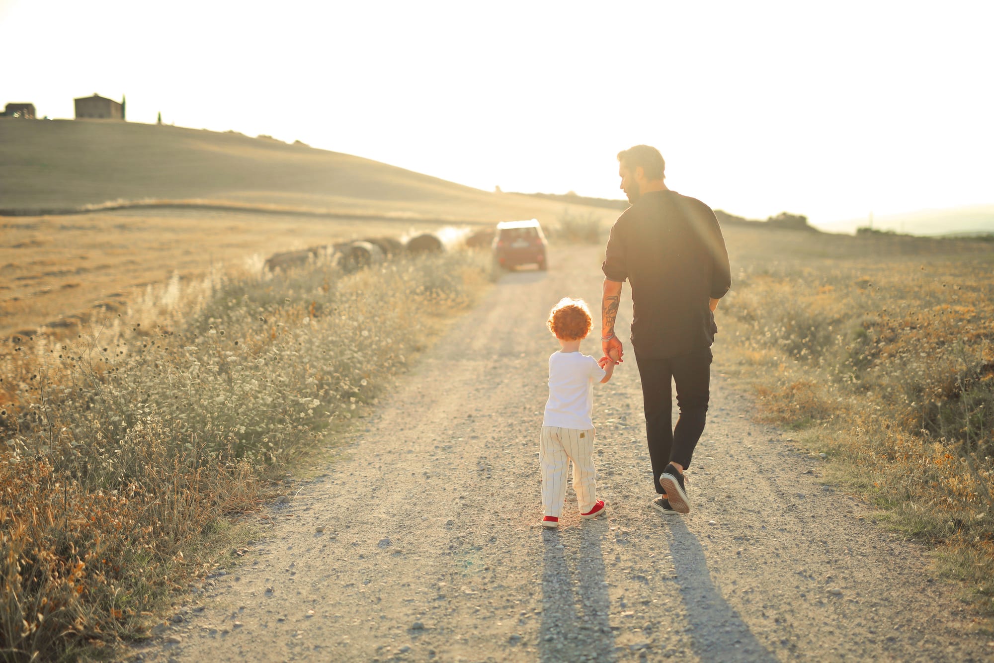A dad and his son walking a country road at sunset